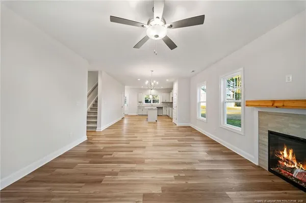 a view of an empty room with a fireplace and a ceiling fan