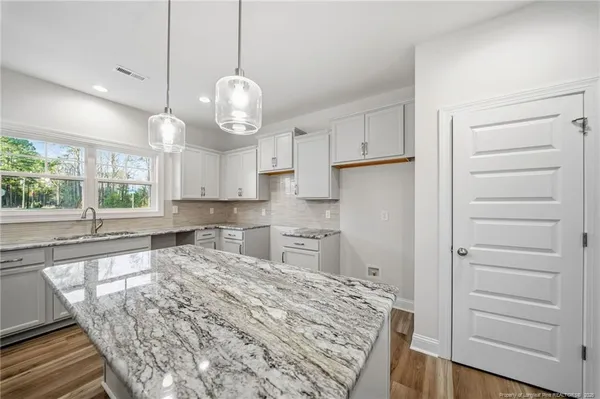 a large kitchen with kitchen island white wooden cabinets and stainless steel appliances