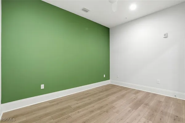 an empty room with wooden floor and fan