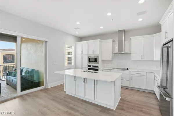 a kitchen with stainless steel appliances a stove a sink a refrigerator and white cabinets with wooden floor