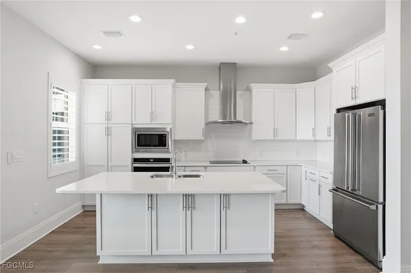 a kitchen with stainless steel appliances a stove a sink a refrigerator and white cabinets