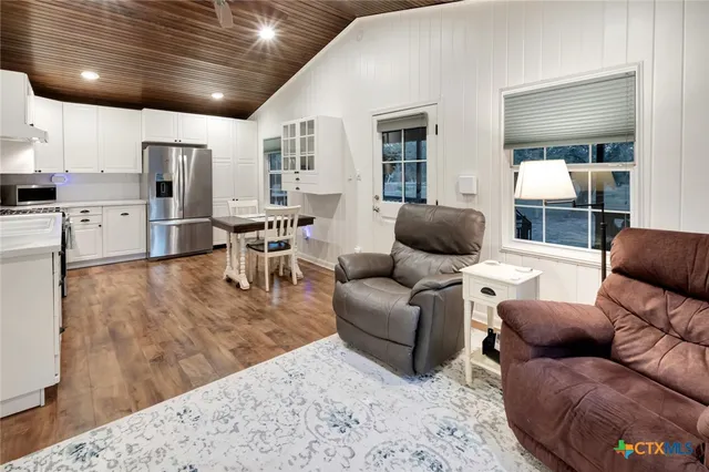 a kitchen with stainless steel appliances kitchen island granite countertop a table chairs sink and cabinets