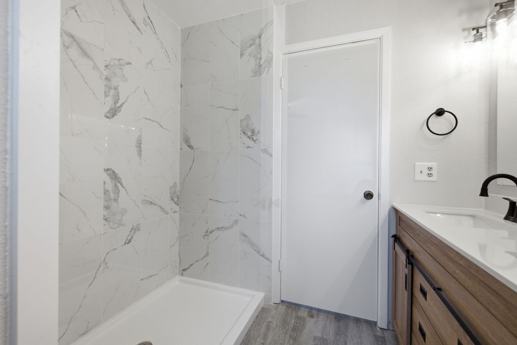1454 Red Town Road Elgin, TX 78621 - Photo 15 of 40 A well-appointed bathroom offers a shower with elegant tile walls and a vanity with a dark wood finish.
