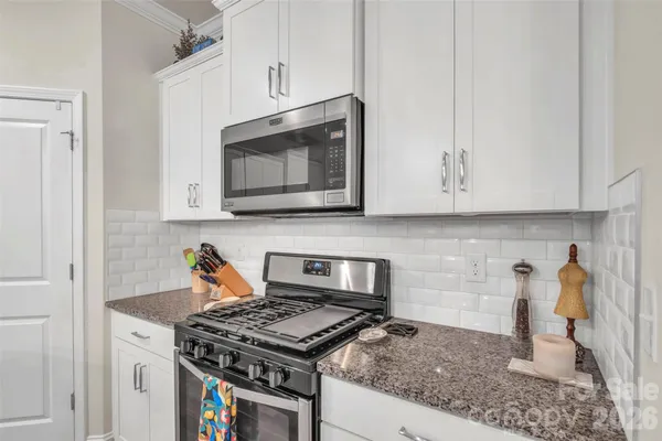 a kitchen with stainless steel appliances granite countertop white cabinets and a stove top oven