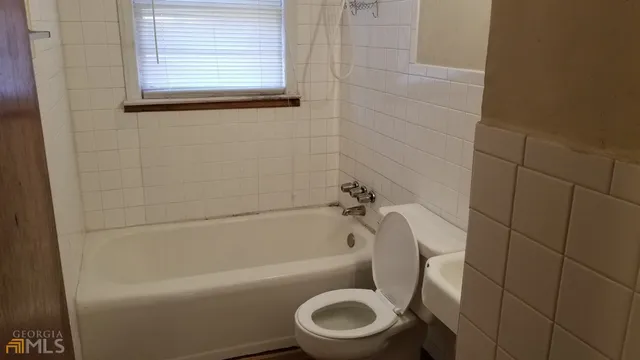 a white toilet sitting next to a bath tub