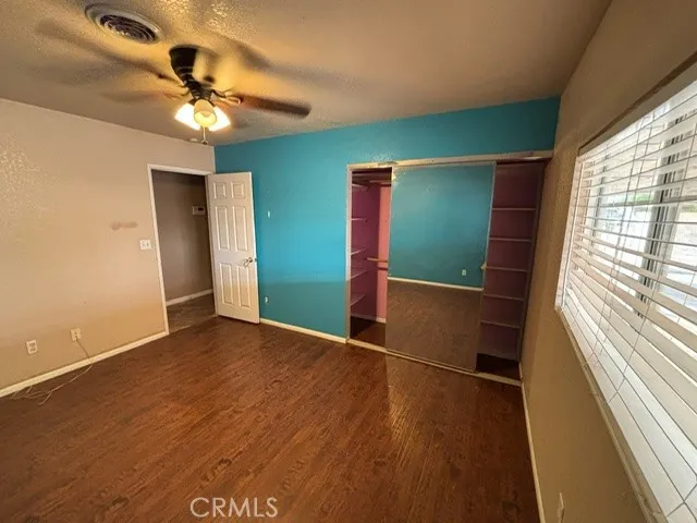 an empty room with wooden floor fan and windows