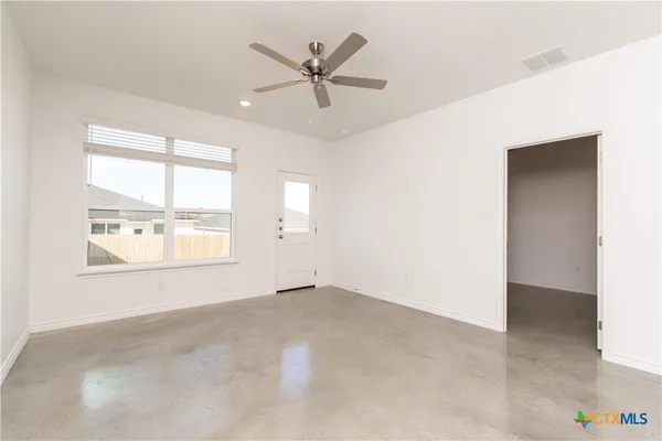 an empty room with a window and a ceiling fan