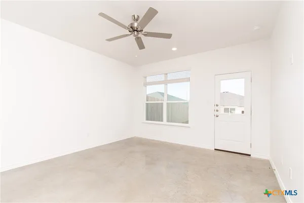 an empty room with windows and ceiling fan