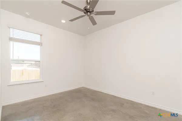 an empty room with a window and a fan