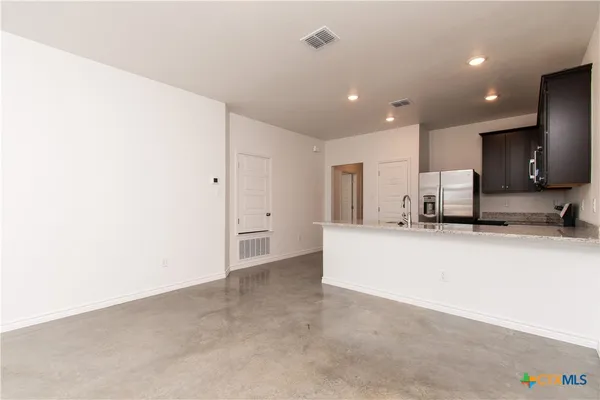 a view of kitchen with kitchen island a sink a stove and a refrigerator with wooden floor