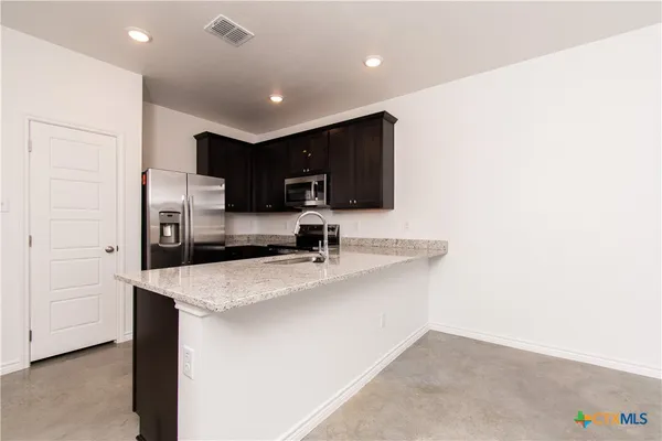 a kitchen with stainless steel appliances granite countertop a sink refrigerator and microwave