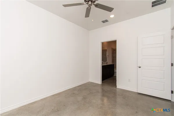 an empty room with a ceiling fan and carpet