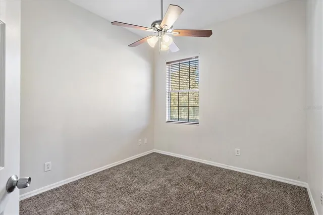 an empty room with windows and fan