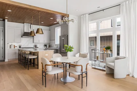 a dining room with stainless steel appliances kitchen island granite countertop a table chairs and a view of living room