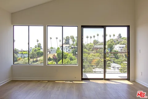a view of an empty room with wooden floor and a window