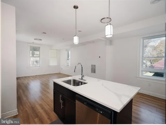 a view of a kitchen with a sink a window and wooden floor