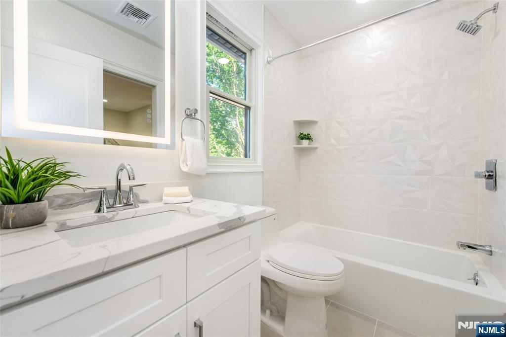 145 Grove Street Mahwah, NJ 07430 - Photo 20 of 30 a bathroom with a granite countertop sink a toilet and shower