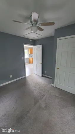 an empty room with a chandelier fan and windows