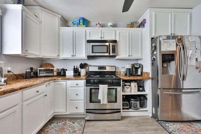 a kitchen with stainless steel appliances granite countertop a refrigerator sink and stove