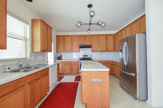 a kitchen with stainless steel appliances granite countertop a sink refrigerator stove and microwave