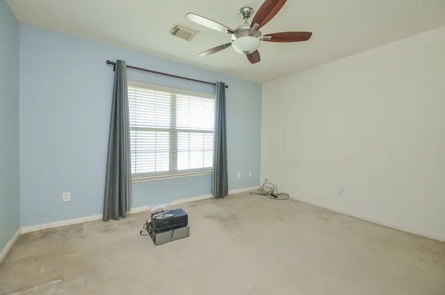 an empty room with windows and fan