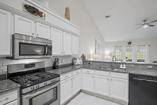 a kitchen with stainless steel appliances granite countertop a stove a sink and a microwave