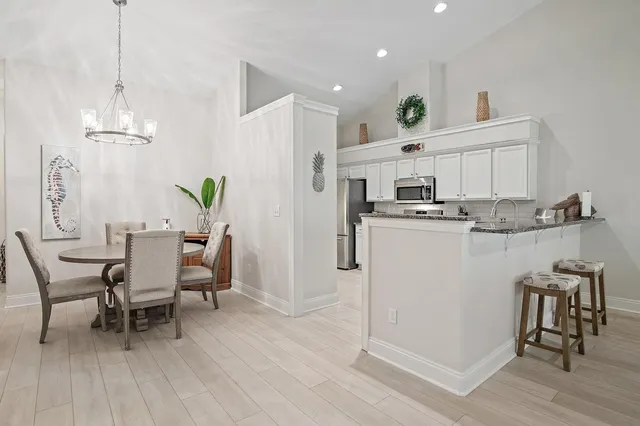 a kitchen with stainless steel appliances a dining table chairs refrigerator and microwave