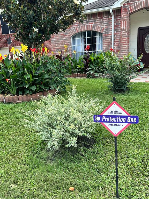 a sign that is sitting in front of a brick house with a small yard