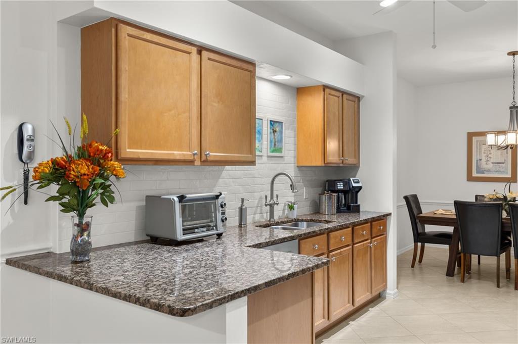 23164 Grassy Pine Drive Estero, FL 33928 - Photo 12 of 43 a kitchen with stainless steel appliances granite countertop a sink table and chairs in it