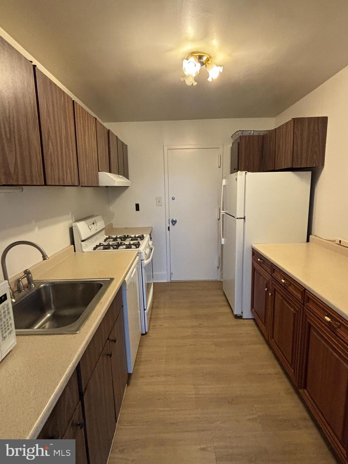 1111 University Boulevard West, Unit 611A Silver Spring, MD 20902 - Photo 13 of 26 a kitchen with a sink a stove cabinets and a wooden floor