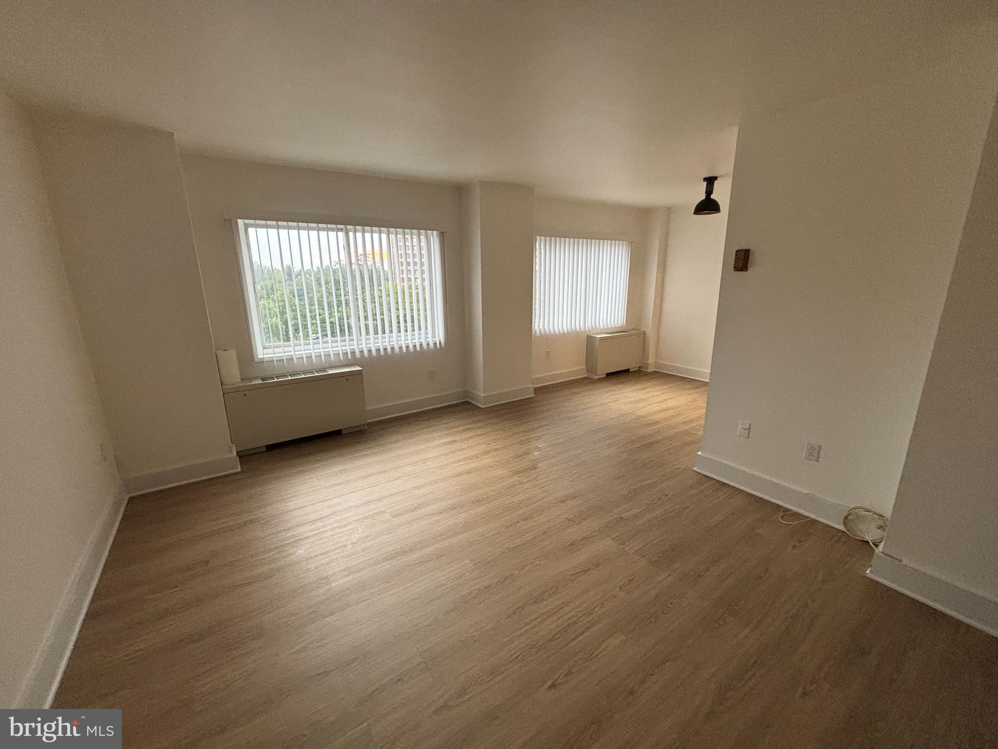 1111 University Boulevard West, Unit 611A Silver Spring, MD 20902 - Photo 3 of 26 an empty room with wooden floor and windows