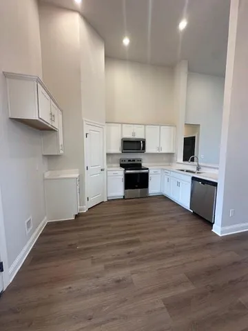 a kitchen with stainless steel appliances a stove a sink wooden floor and a refrigerator