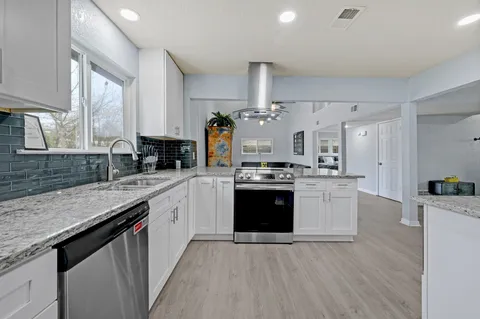 a kitchen with stainless steel appliances granite countertop a stove and a sink