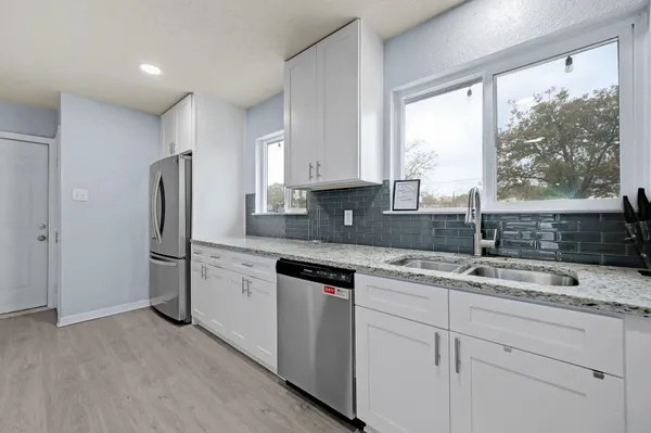 a large kitchen with stainless steel appliances kitchen island granite countertop a sink cabinets and wooden floor