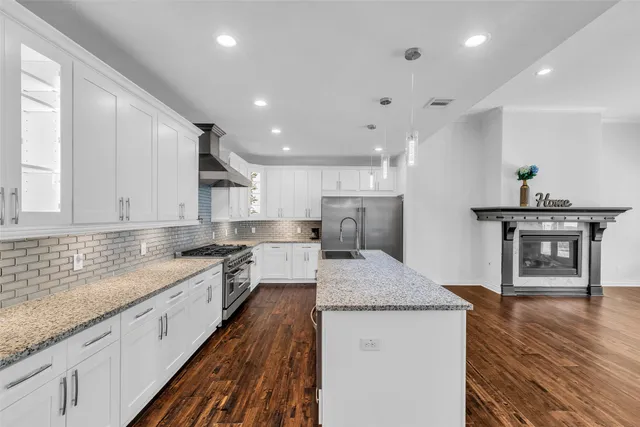 a large kitchen with stainless steel appliances granite countertop a lot of counter space and wooden floor