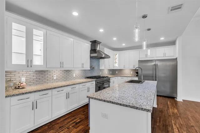 a kitchen with stainless steel appliances granite countertop a sink a stove and a refrigerator