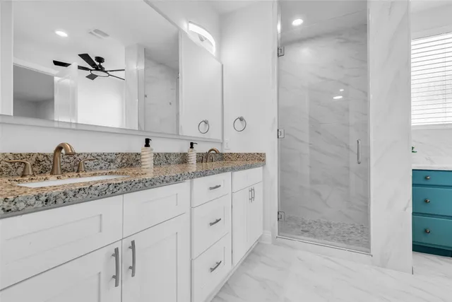a bathroom with a granite countertop sink two mirror and shower