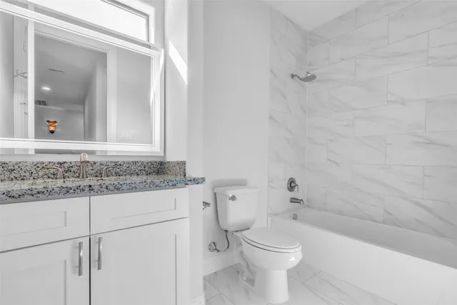 a bathroom with a granite countertop toilet a sink and a bathtub