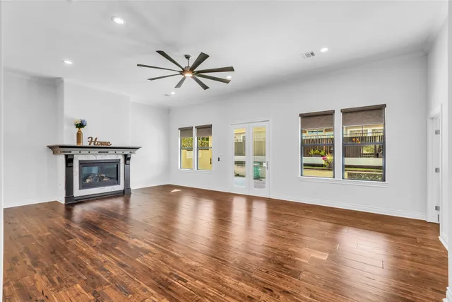 a view of an empty room with a window and wooden floor