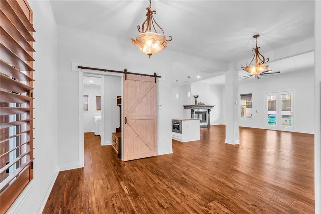 a view of empty room with wooden floor and kitchen view