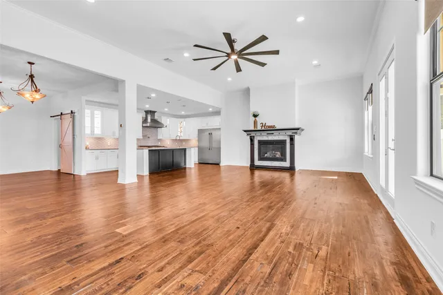a view of a livingroom with a ceiling fan wooden floor and a kitchen