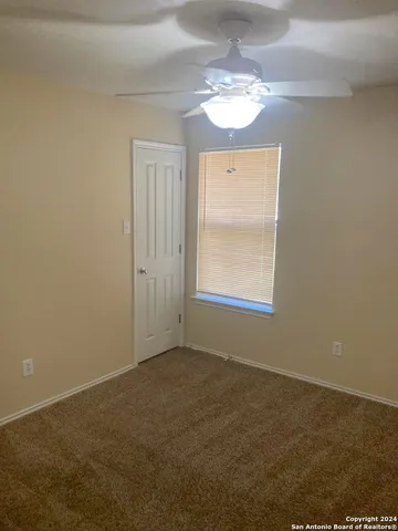 en empty room with windows and chandelier fan