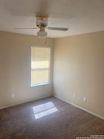 en empty room with windows and chandelier fan