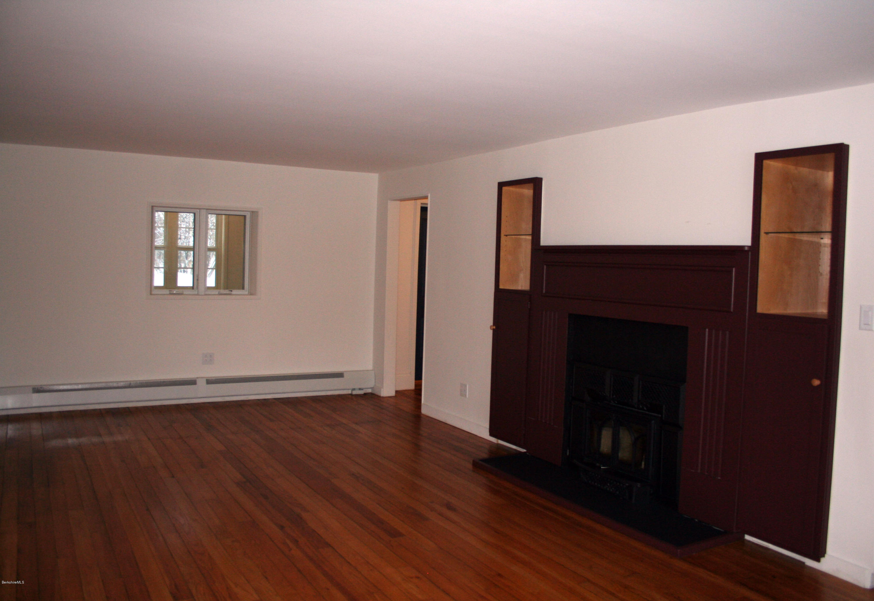945 State Road Richmond, MA 01254 - Photo 24 of 32 an empty room with wooden floor a fireplace and windows