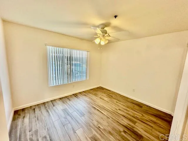 a view of empty room with wooden floor and fan