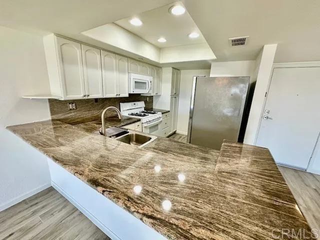 a kitchen with granite countertop a sink a counter top space cabinets and stainless steel appliances