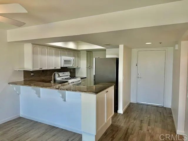a kitchen with stainless steel appliances granite countertop a sink and a refrigerator