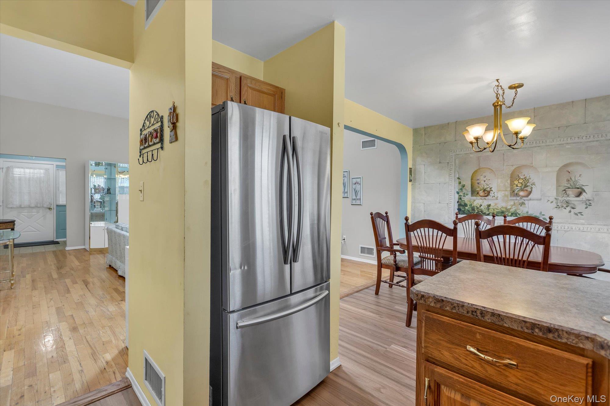 20 Primrose Lane North Babylon, NY 11703 - Photo 9 of 19 a kitchen with granite countertop a refrigerator a stove a dining table and chairs with wooden floor