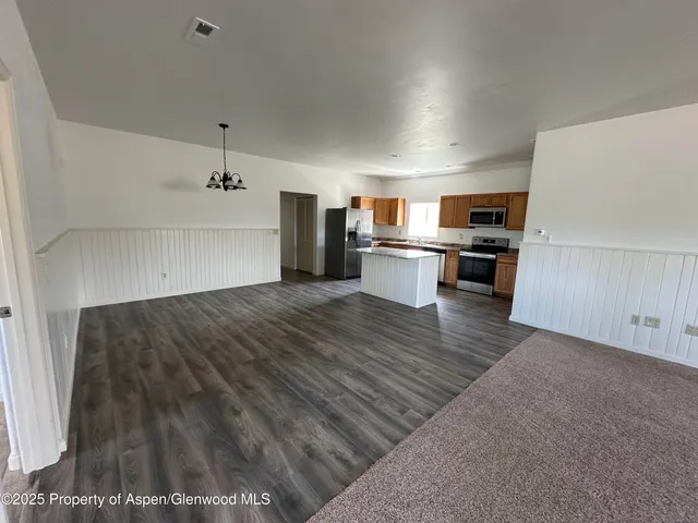 a open kitchen with kitchen island a stove a sink dishwasher and a refrigerator with wooden floor