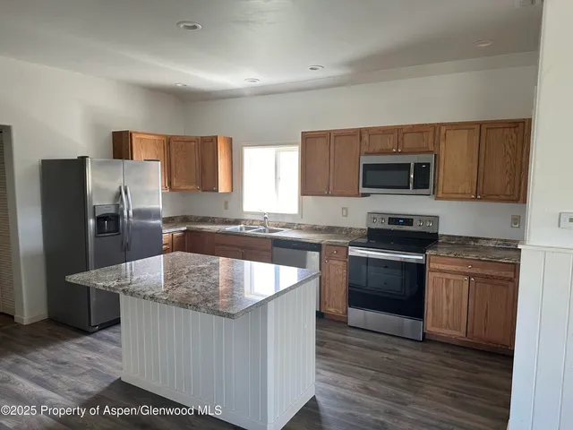 a kitchen with stainless steel appliances granite countertop a sink stove microwave and refrigerator